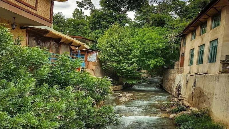 خانه های روستای برغان در جوار رودخانه و بوته های سبز